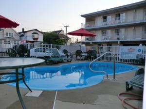 a swimming pool with a table and chairs and a building at Bay Breeze Motel in Seaside Heights