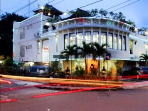 a large white building with palm trees in front of it at Hotel Mataram 2 Malioboro in Yogyakarta