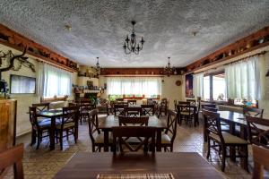 a restaurant with wooden tables and chairs and windows at Guesthouse Alexandros in Nestorio