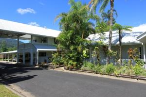 een huis met palmbomen voor een straat bij Tully Motel in Tully