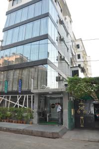 un homme debout devant un grand bâtiment dans l'établissement Hotel Esteem, à Kolkata