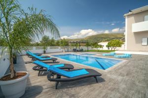 una fila di sedie a sdraio blu accanto alla piscina di Ostria Luxury Villa a Pandokrátor