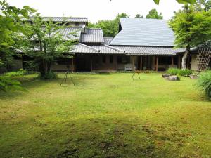 una casa con césped delante en Shikinosato Hanamura, en Minamioguni
