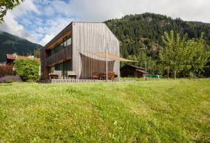 a building in a field next to a grass field at Ferienhaus Alpin in Neustift im Stubaital