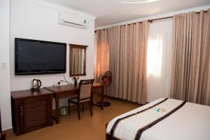 a hotel room with a desk with a bed and a television at Ocean Star Hotel in Vung Tau