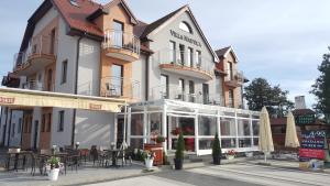 a building with tables and chairs in front of it at Villa Nautica in Mrzeżyno