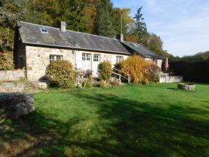 a stone house with a grass yard in front of it at Le Moulin L'Eveque in Campeaux