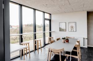 a dining room with a table and chairs and large windows at Guesthouse Klitmøller in Klitmøller