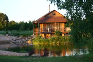 a log cabin with a pond in front of it at Mikalojiškis in Inturkė