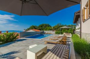 マトゥリにあるApartments Villa Sonjaのパラソルとプールのあるパティオ