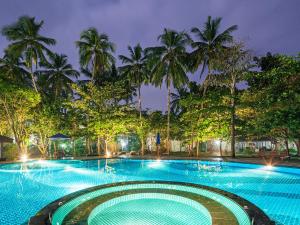 a large swimming pool with palm trees at night at Siddhalepa Ayurveda Resort - All Meals, Ayurveda Treatment and Yoga in Wadduwa