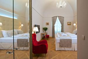 una camera d'albergo con due letti e una sedia rossa di Zámek Ratměřice - Hotel & Resort a Ratměřice Altre 37 foto
