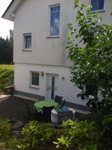 a white house with a green table in front of it at Ferienwohnung am Nurburgring in Welcherath