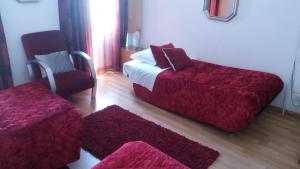a bedroom with a bed and a chair and red sheets at Alojamento Cesarini in Montijo