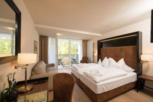 a hotel room with a large bed and a desk at Genusshotel Goldene Rose in Silandro