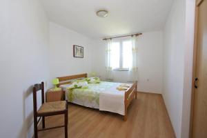 a bedroom with a bed and a chair and a window at Marašić in Ždrelac