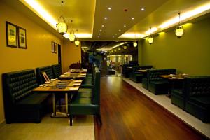 un restaurante con paredes y mesas verdes y sillas verdes en Leisure Stays - Premium Suites, en Chennai