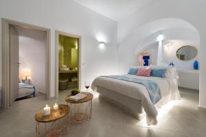 a white bedroom with a large bed and a bathroom at Kima Oia Suites in Oia