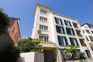un alto edificio bianco con alberi di fronte di Apartamentos Turisticos Avenue Park a Funchal