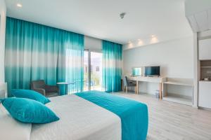 a bedroom with a large bed and blue curtains at Anesis Hotel in Ayia Napa