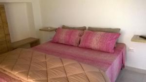 Schlafzimmer mit einem Bett mit rosa Bettwäsche und Kissen in der Unterkunft B&B Stella Maris in Magomadas