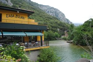 un bâtiment à côté d'une rivière à côté d'une montagne dans l'établissement Hotel Casa Julián, à Peñamellera Alta
