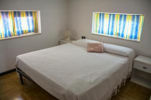 a bed in a bedroom with two windows at La casa di Titta in Di Natale