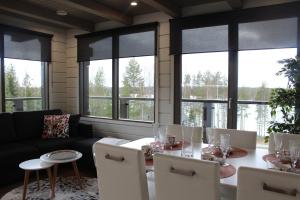 a living room with a table and chairs and windows at Naava Chalets in Ähtäri