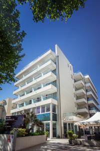 里米尼的住宿－克里斯塔羅酒店，一座白色的大建筑,前面设有一个游泳池