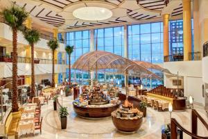a large lobby with tables and chairs and palm trees at Corinthia Tripoli in Tripoli