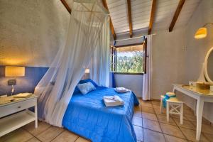 Un dormitorio con una cama azul y una ventana en Glyfada Beach Villas, en Longós