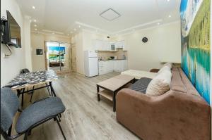 a living room with a couch and a table and a kitchen at Studio on Dostyq Street 5 floor 25 in Astana +12 photos