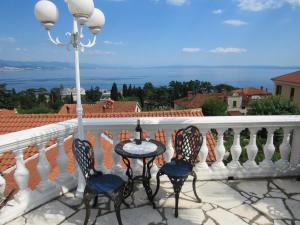 een balkon met een tafel en stoelen en de oceaan bij Apartments Villa Palme in Opatija