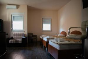 a room with four beds and a chair and windows at Apartments Dujmović in Međugorje