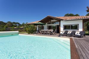 a house with a swimming pool in front of a house at Madame Vacances Villas La Prade in Moliets-et-Maa