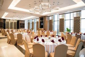 ダナンにあるMuong Thanh Luxury Danang Beach Hotelの白いテーブルと椅子が置かれた宴会場 +85枚の写真