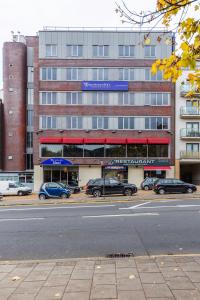 un gran edificio con coches estacionados en un estacionamiento en Eurotraveller Hotel - Premier - Harrow en Harrow