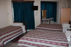 two beds in a hotel room with blue curtains at Delphi Hotel in Nicosia