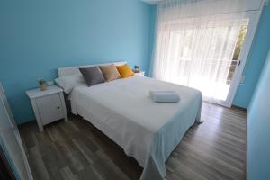 Cama en habitación azul con ventana grande en Apartamento Playa Capellans - Salou, en Salou