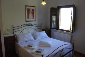 a bedroom with a bed with white sheets and a window at Vignano40 in Siena