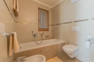 a bathroom with a tub and a toilet and a sink at Ciasa Dolomites in La Villa