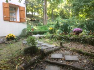 un jardín con una casa y algunas plantas en Nobuta Vendégház, en Kismaros