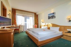 una camera da letto con un letto, una scrivania e una televisione di Hotel Tiroler Adler - bed and breakfast a Waidring