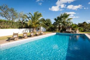 a swimming pool with chairs and palm trees at Can Caseres in Santa Eularia des Riu