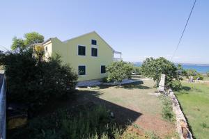 a yellow house on a hill with a yard at Marašić in Ždrelac