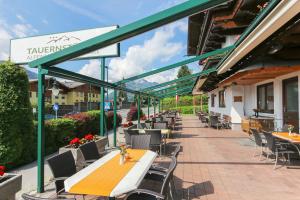 eine Terrasse mit Tischen und Stühlen auf einem Gebäude in der Unterkunft Alpenhotel Tauernstüberl in Zell am See