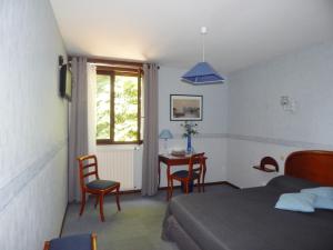 a bedroom with a bed and a table and chairs at Hotel Restaurant Le Cygne in Conches-en-Ouche