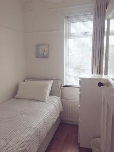Belfast Holiday Home في بلفاست: غرفة نوم صغيرة بها سرير ونافذة