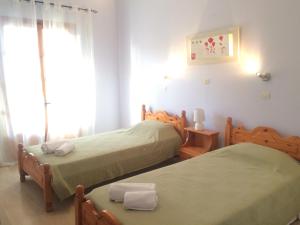 una camera da letto con due letti e una finestra di Nikos Apartments a Sidari Altre 12 foto