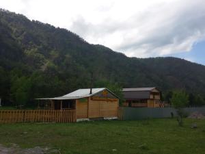 a small wooden building in a field with a mountain at Selskaya Usadba in Uznezya